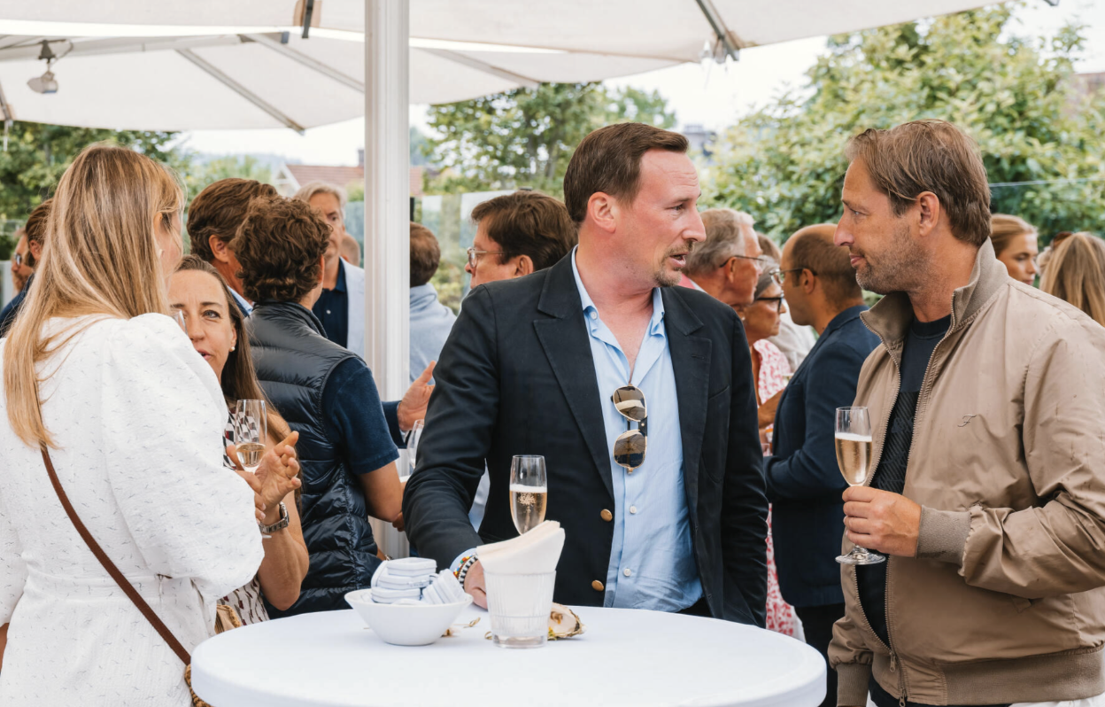 Gäster minglar med champagne under parasoller på Villa Pauli